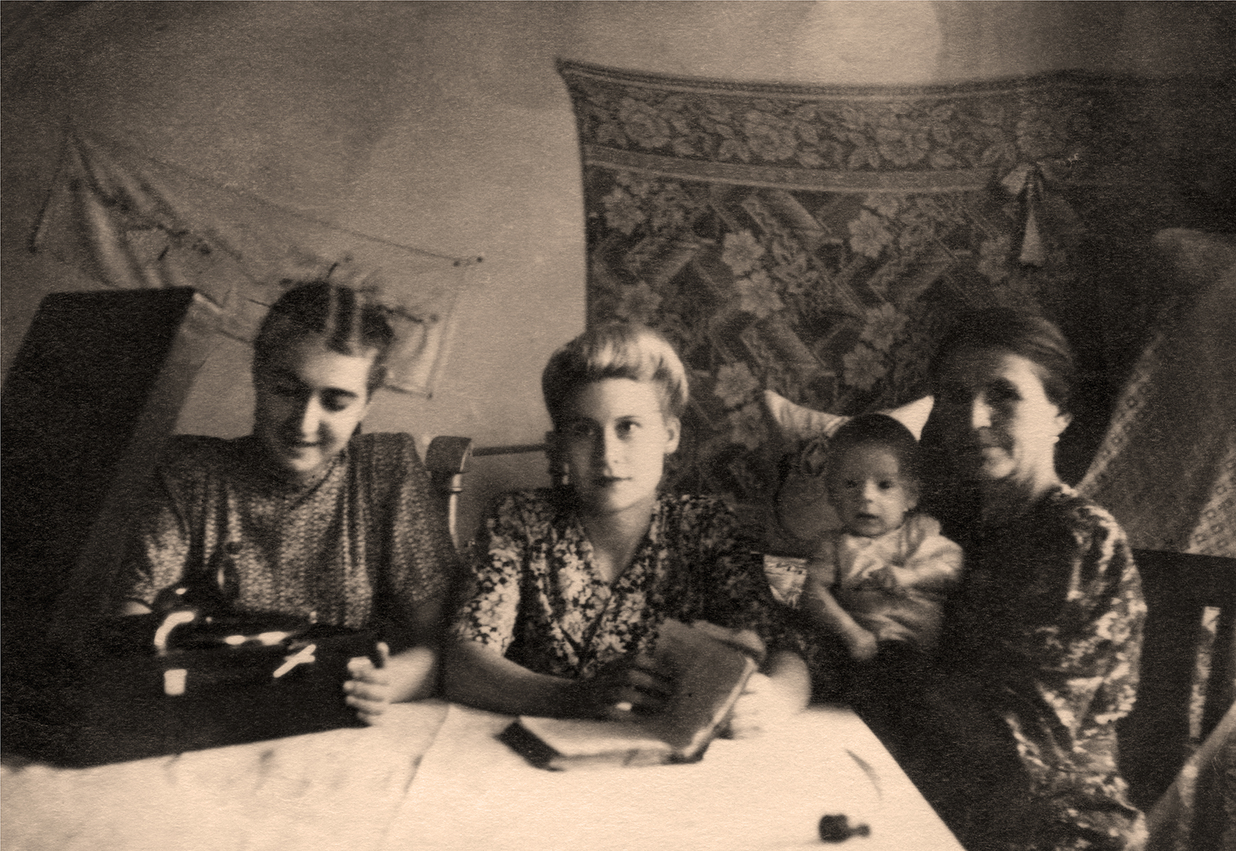 A group of women sitting at a table with one baby.